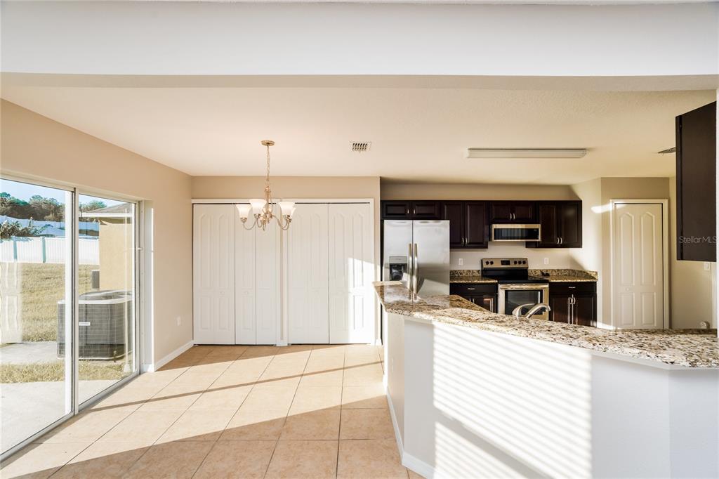 A kitchen and dining area feature tile flooring, granite countertops, and dark wood cabinetry — 13307 WATERFORD CASTLE DRIVE, DADE CITY, FL