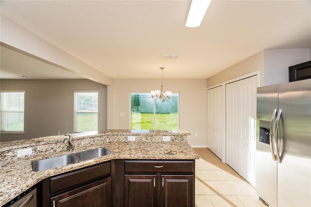 A kitchen features dark wood cabinets, granite countertops, a double sink, and stainless steel appliances — 13307 WATERFORD CASTLE DRIVE, DADE CITY, FL