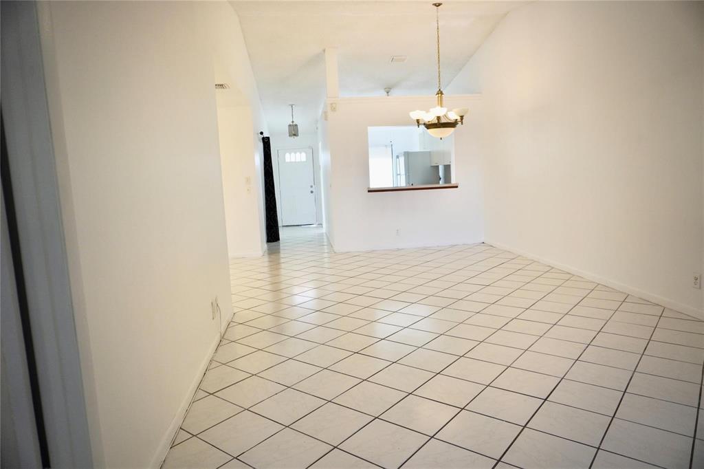A dining area with white tiled floors and a chandelier, looking toward a kitchen pass-through — 5600 N Park, Dania Beach FL 33312, DANIA BEACH, FL
