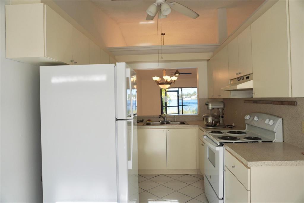 A kitchen features white appliances, light-colored cabinetry, laminate countertops, and a window overlooking water — 5600 N Park, Dania Beach FL 33312, DANIA BEACH, FL