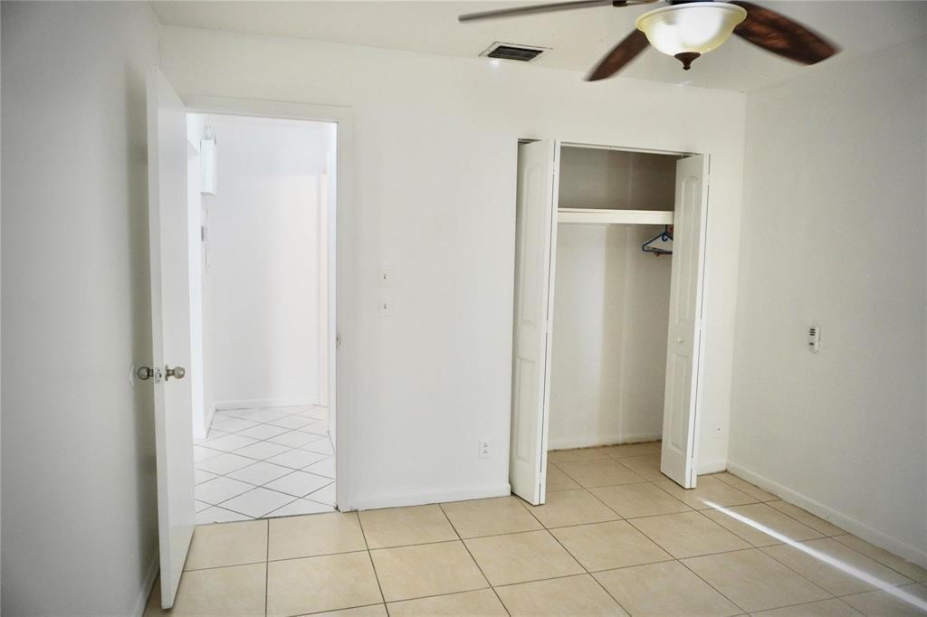 A bedroom features white walls, beige tile flooring, a ceiling fan, and an open closet — 5600 N Park, Dania Beach FL 33312, DANIA BEACH, FL