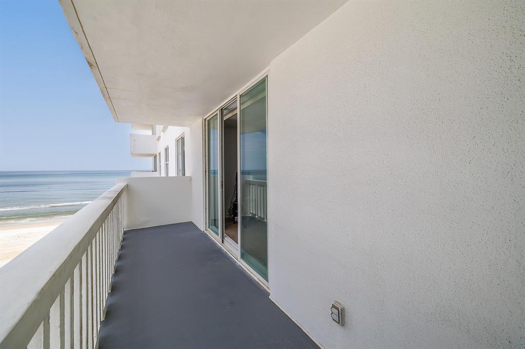 A balcony with a gray floor, white railing, and sliding glass doors overlooking the ocean — 2800 N ATLANTIC AVENUE UNIT 511, DAYTONA BEACH, FL