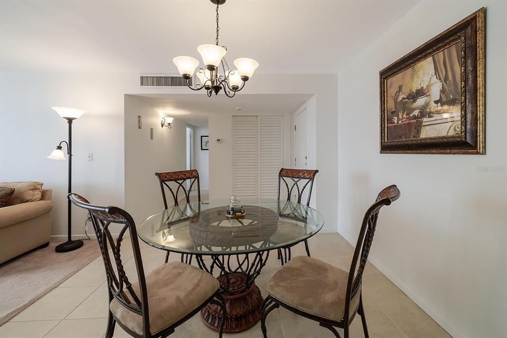 A dining area features a glass-topped table with four chairs under a chandelier — 2800 N ATLANTIC AVENUE UNIT 511, DAYTONA BEACH, FL