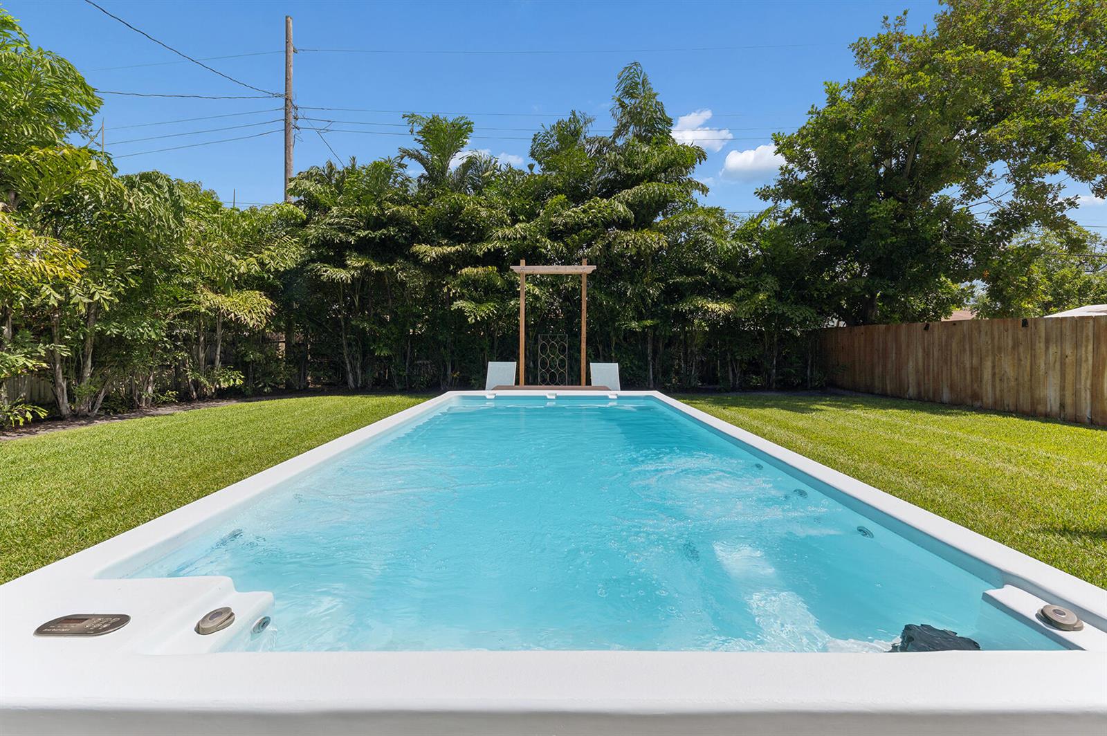 A rectangular swimming pool sits in a grassy backyard with a wooden arbor behind it — 127 SW 10th Avenue, Boynton Beach FL 33435, BOYNTON BEACH, FL