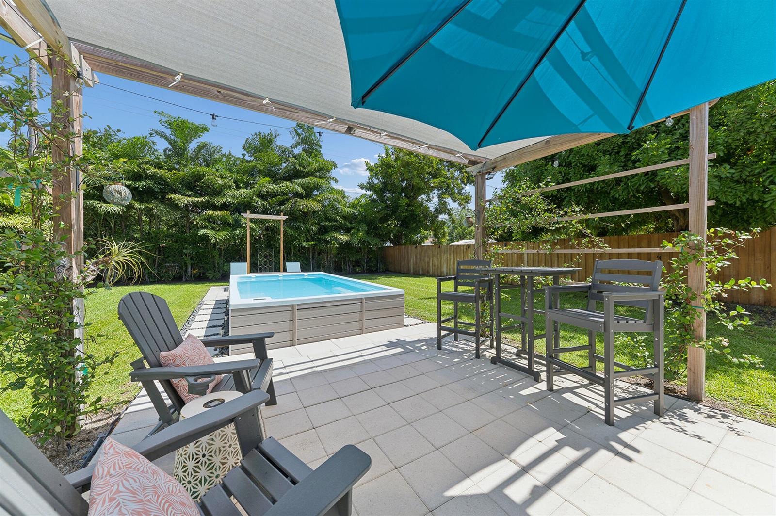 A backyard patio features a small above-ground pool, a dining set, and Adirondack chairs — 127 SW 10th Avenue, Boynton Beach FL 33435, BOYNTON BEACH, FL