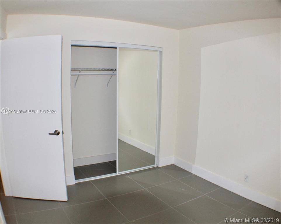 A bedroom features light-colored walls, gray tile flooring, and a closet with mirrored sliding doors — 719 SW 7th Street # 2, Hallandale Beach FL 33009, HALLANDALE BEACH, FL