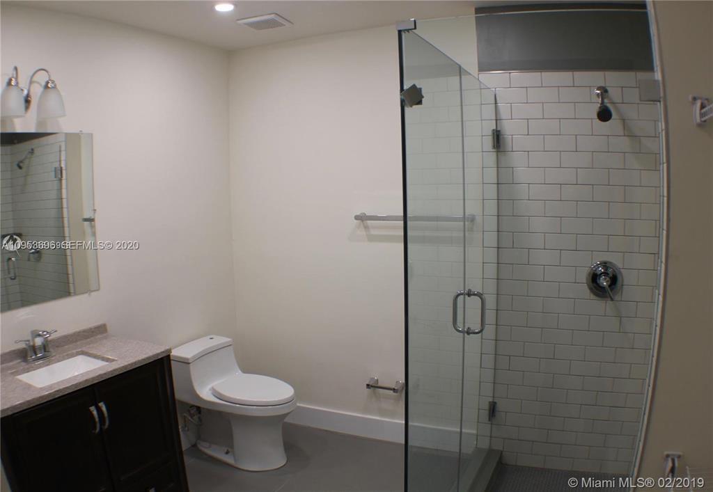 A bathroom features a vanity, a toilet, and a glass-enclosed shower with white subway tiles — 719 SW 7th Street # 2, Hallandale Beach FL 33009, HALLANDALE BEACH, FL