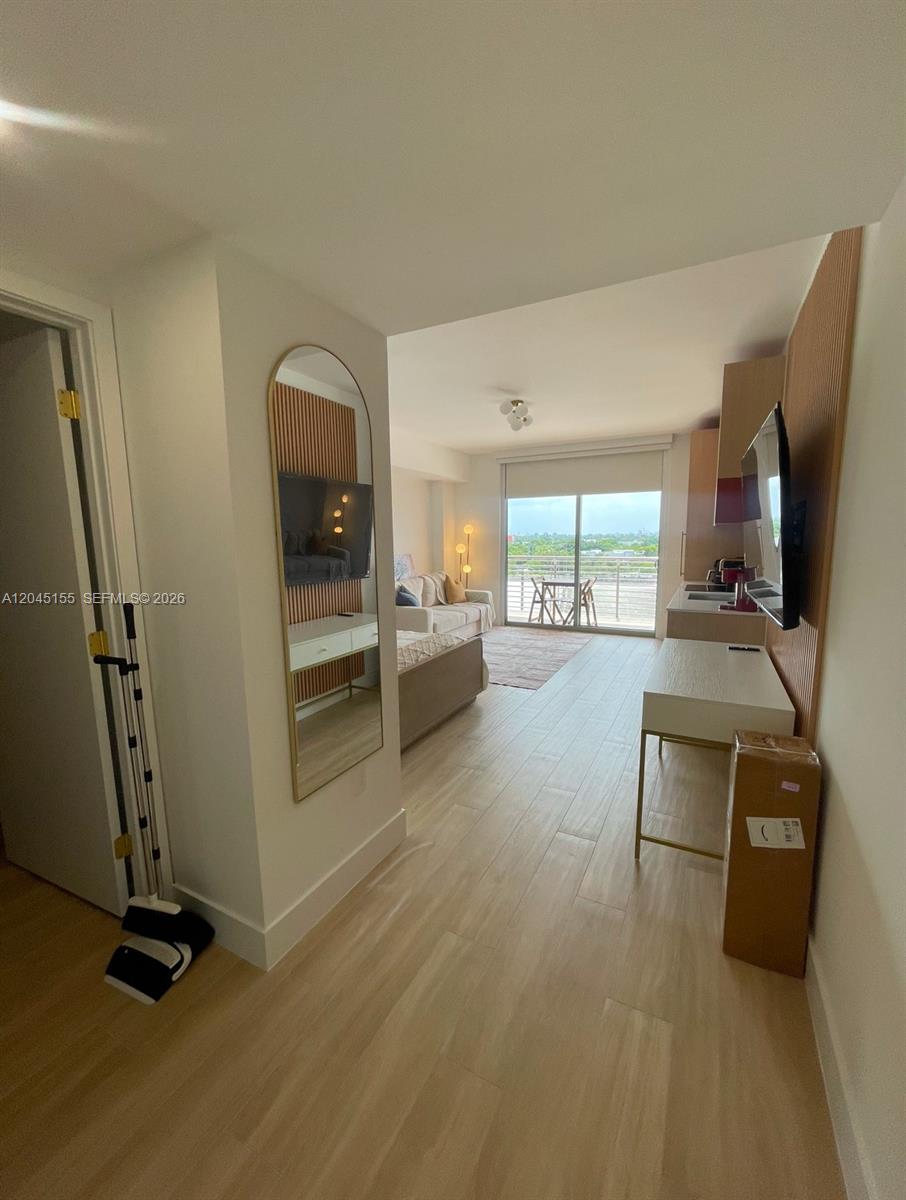 A studio apartment features light wood flooring, a kitchenette, and a balcony with outdoor seating — 90 NE 32 # 819, Miami FL 33137, MIAMI, FL