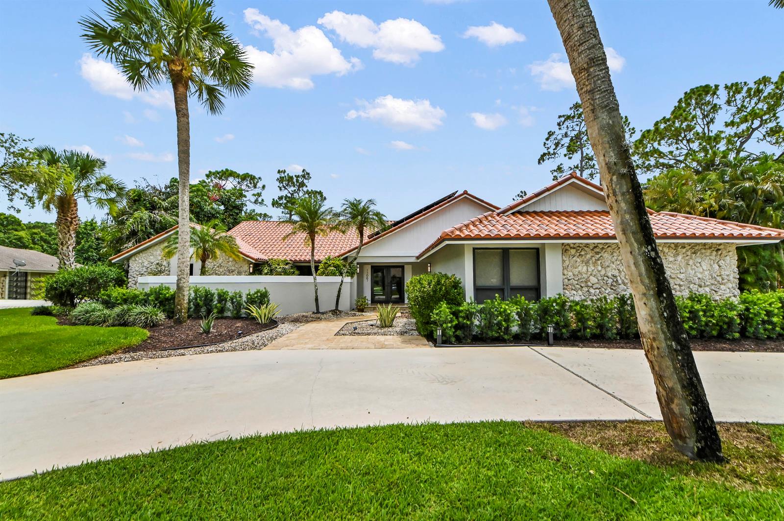 A single-story house with a tile roof, stone facade, and a paved driveway — 13067 Doubletree Circle, Wellington FL 33414, WELLINGTON, FL