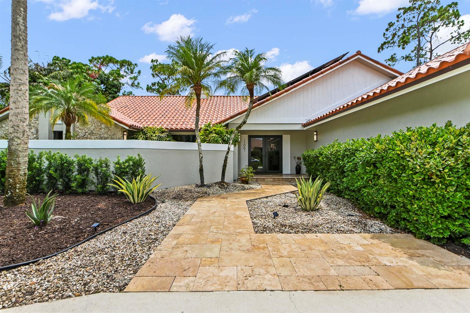 A paved walkway leads to the front entrance of a house with a tiled roof — 13067 Doubletree Circle, Wellington FL 33414, WELLINGTON, FL