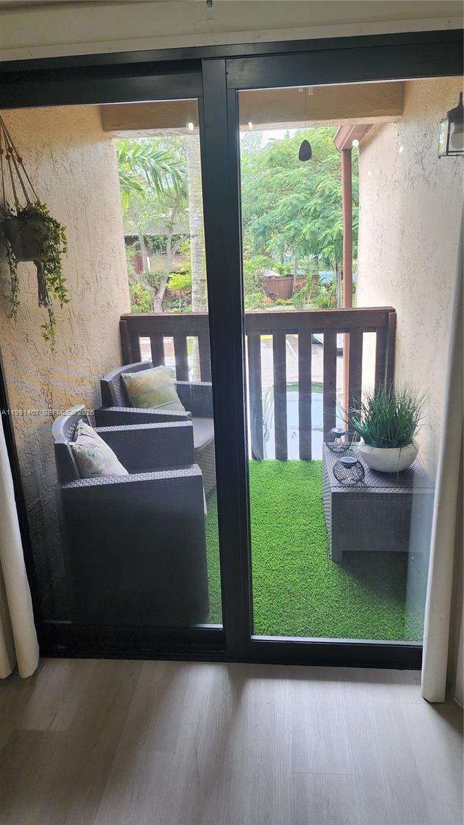 A balcony with artificial grass, two chairs, and a small table viewed through sliding doors — 6231 SW 116th Pl # C, Miami FL 33173, MIAMI, FL