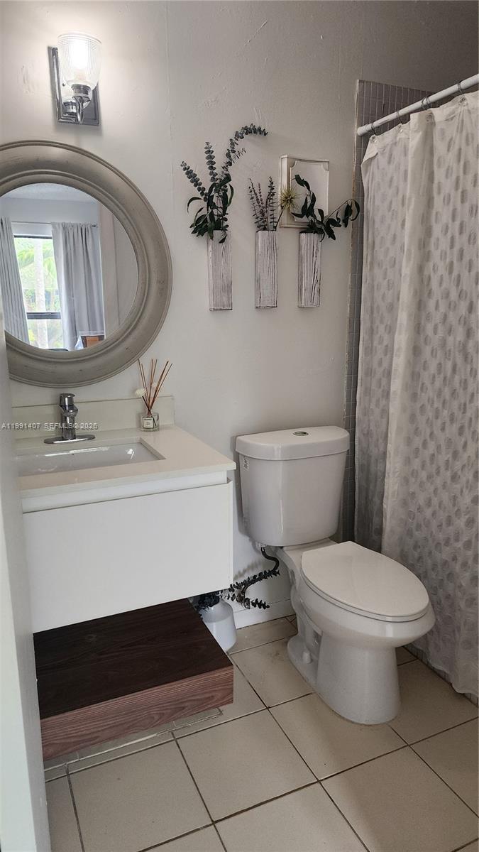 A bathroom features a floating vanity, a round mirror, a toilet, and a shower curtain — 6231 SW 116th Pl # C, Miami FL 33173, MIAMI, FL