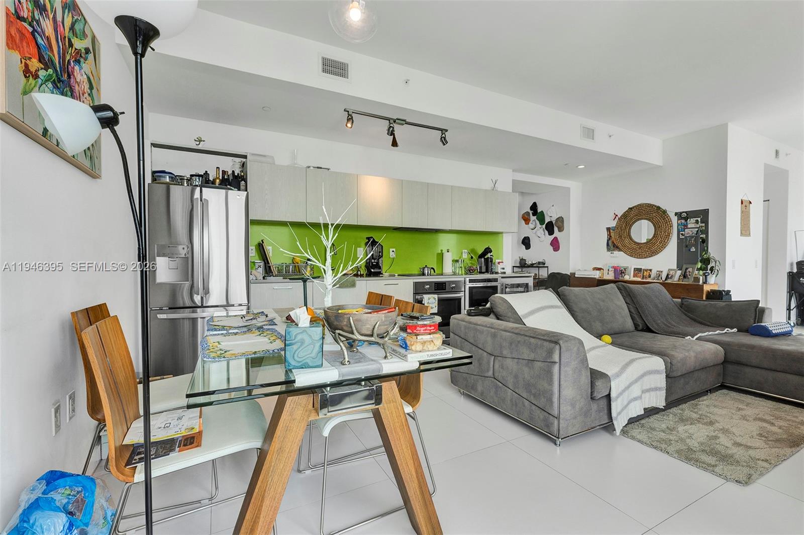 An open-concept living area features a glass dining table, gray sectional sofa, and lime-green backsplash — 501 NE 31 # 4305, Miami FL 33137, MIAMI, FL