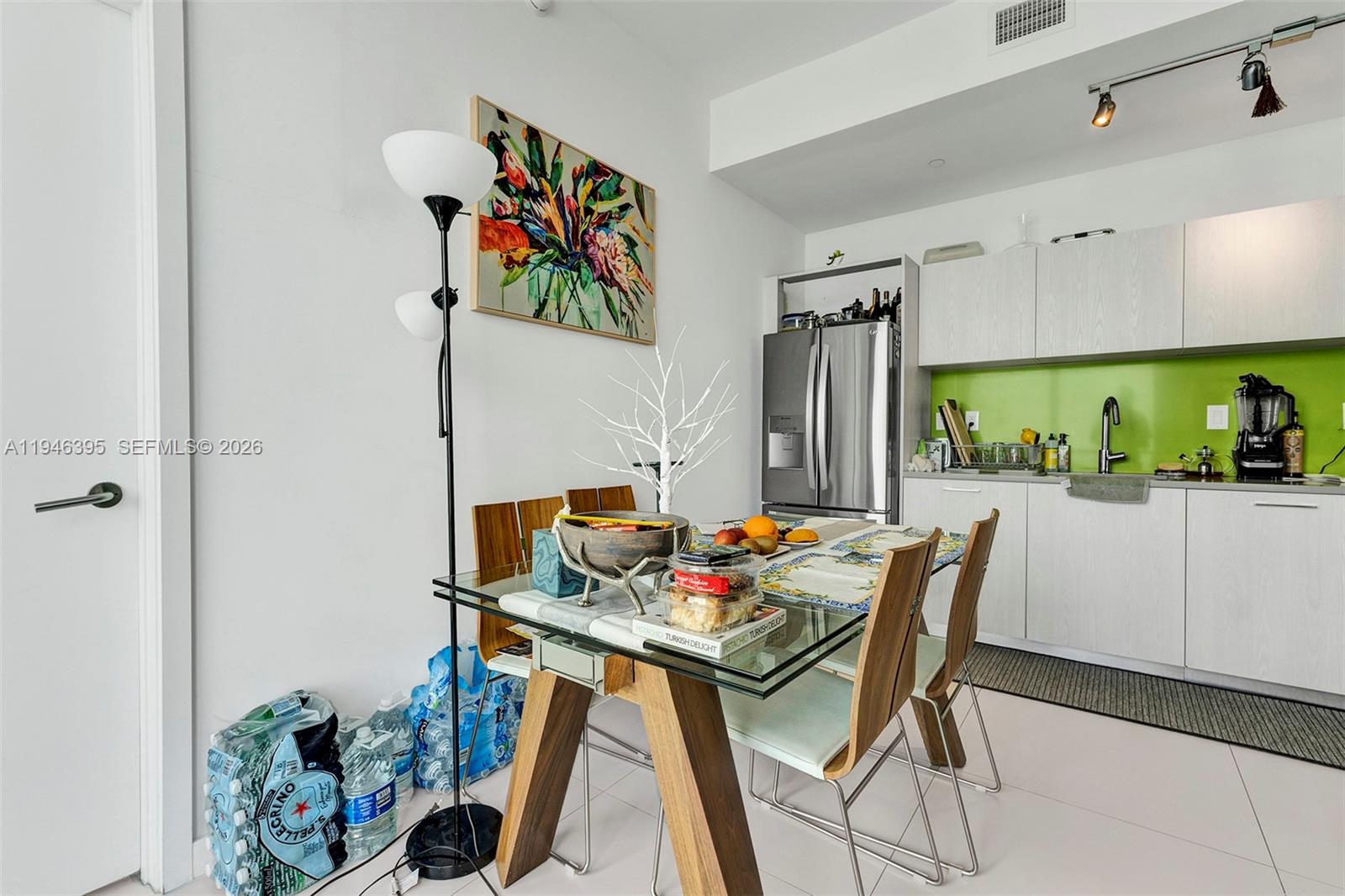 A dining area with a glass table, wooden chairs, and a kitchen with green backsplash — 501 NE 31 # 4305, Miami FL 33137, MIAMI, FL