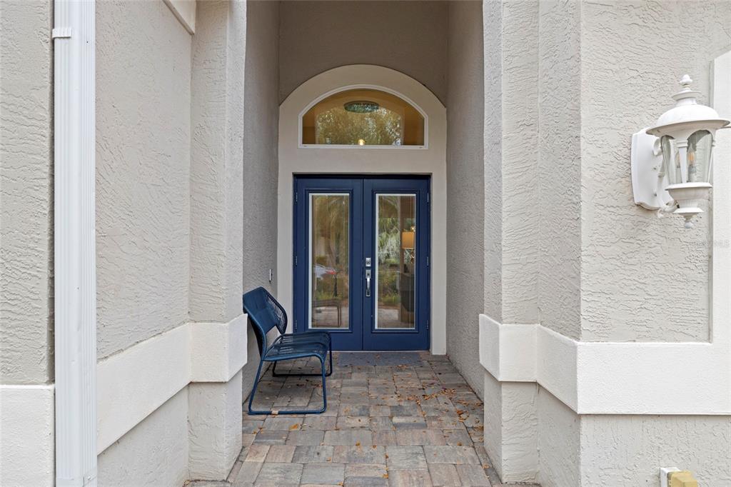 A blue double door with a glass transom sits at the end of a covered entryway — 8322 WHISPERING WOODS COURT, BRADENTON, FL