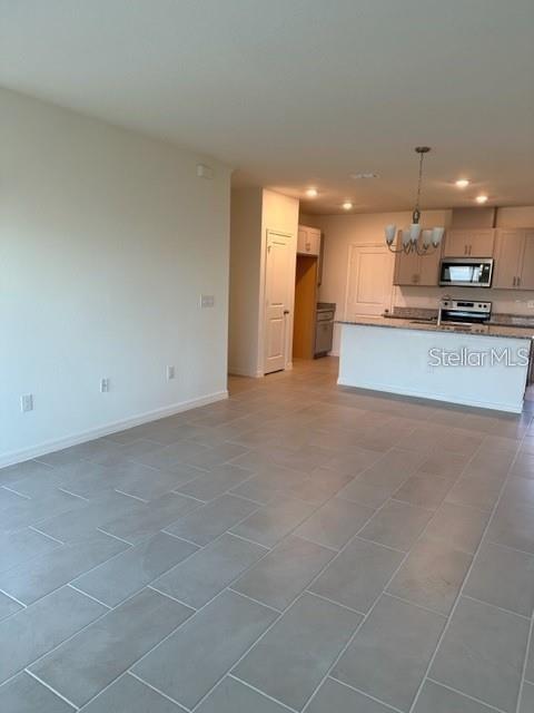 An open-concept kitchen with a white island and light-colored tile flooring — 1548 MIRABELLA CIRCLE, DAVENPORT, FL