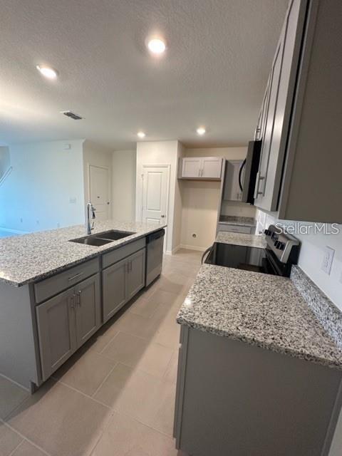 A kitchen features gray cabinets, granite countertops, a center island, and light tile flooring — 1548 MIRABELLA CIRCLE, DAVENPORT, FL