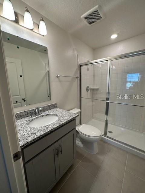 A bathroom features a gray vanity with a granite countertop, a mirror, and a shower — 1548 MIRABELLA CIRCLE, DAVENPORT, FL