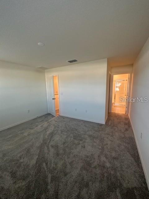 An empty bedroom features gray carpeting, white walls, and two doorways leading to other rooms — 1548 MIRABELLA CIRCLE, DAVENPORT, FL