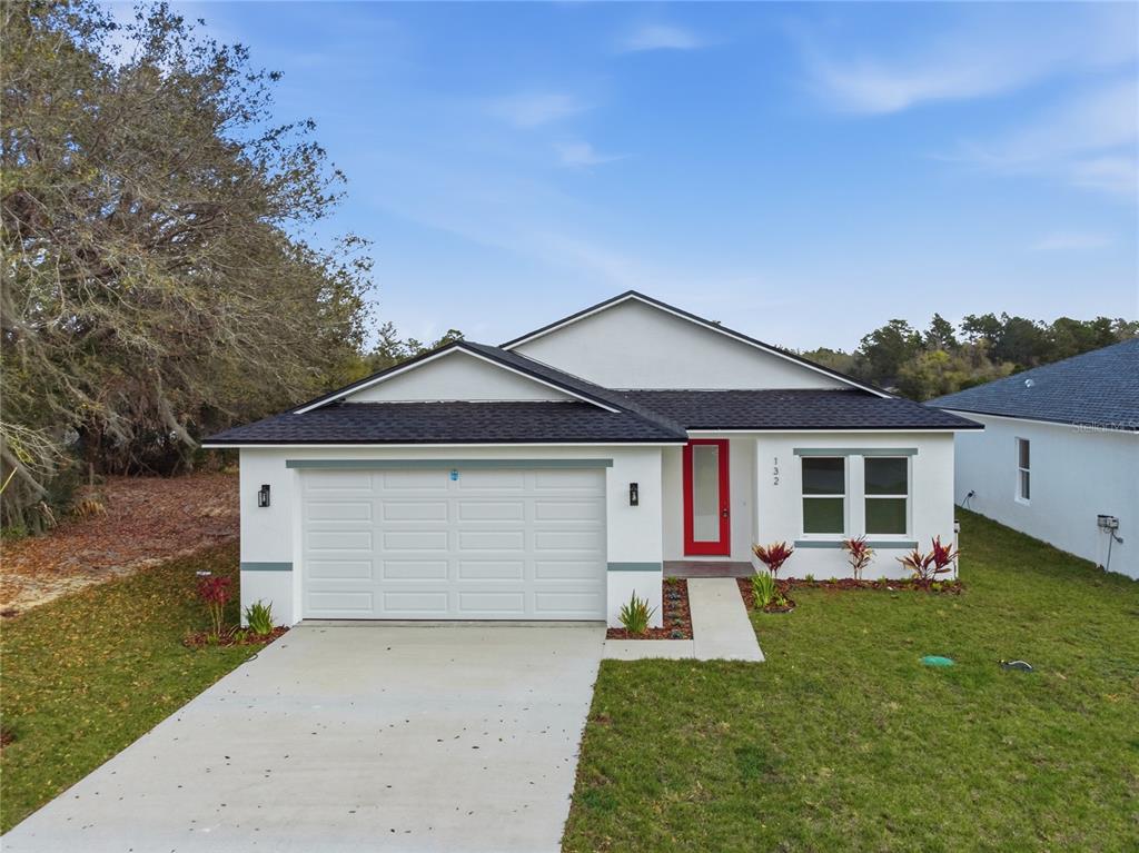 A single-story house with a white exterior, a red front door, and a two-car garage — 132 11TH AVENUE, OSTEEN, FL