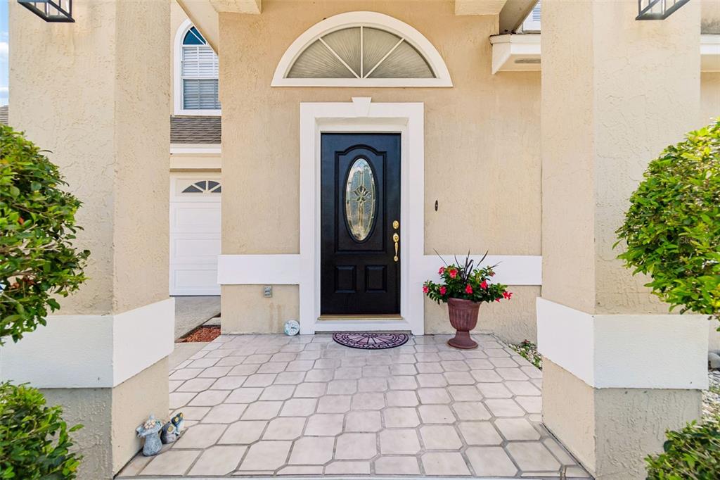 A black front door with a glass insert sits under a semi-circular transom window — 10735 SE DRUMMOND ROAD, TAMPA, FL