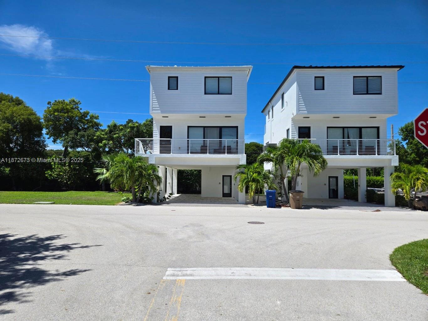 Two modern white multi-story houses stand side-by-side with elevated living areas and ground-level parking — 94825 Overseas Hwy #281, Key Largo FL 33037, KEY LARGO, FL