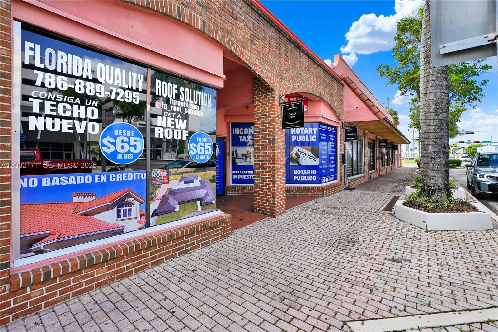 A brick storefront features large window advertisements for roofing services and tax preparation — 1 S Krome Ave, Homestead FL 33030, HOMESTEAD, FL