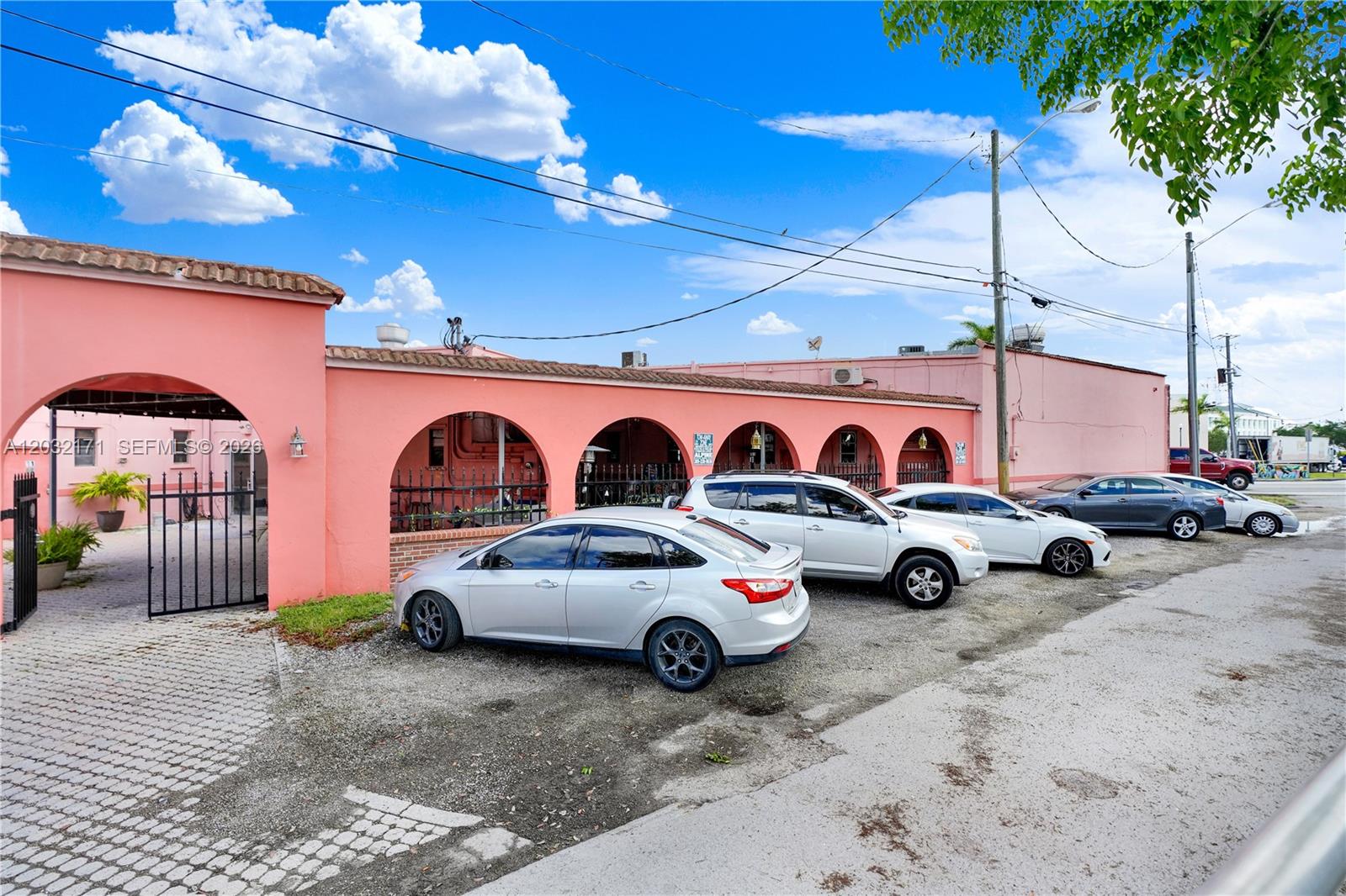 A pink building with arched exterior walkways features a row of parked cars — 1 S Krome Ave, Homestead FL 33030, HOMESTEAD, FL