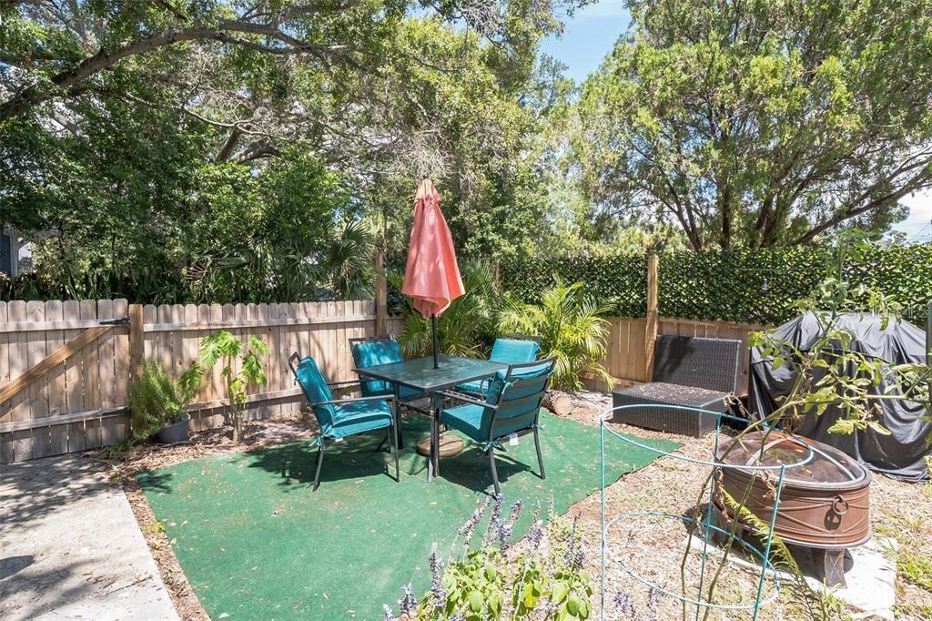 A backyard patio features a table with chairs, a closed umbrella, and a fire pit — 201 35TH STREET S, ST PETERSBURG, FL