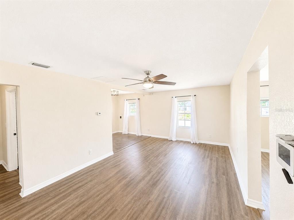 A bright living room features light-colored walls, wood-look flooring, and a ceiling fan — 201 35TH STREET S, ST PETERSBURG, FL