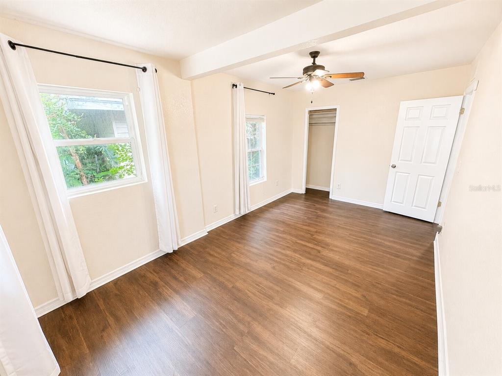 An empty room features wood-look flooring, white walls, a ceiling fan, and two windows — 201 35TH STREET S, ST PETERSBURG, FL