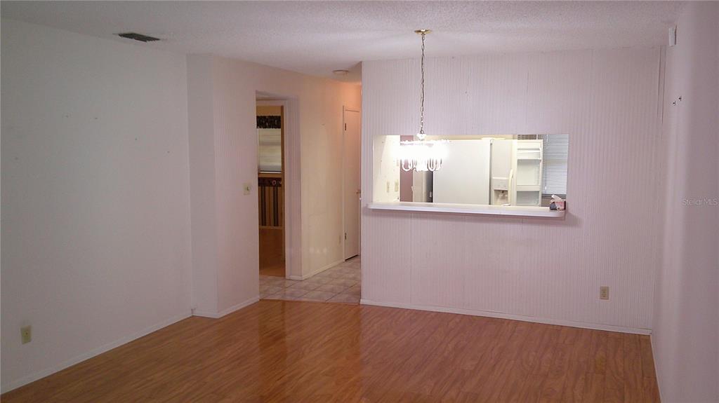 A living room with wood-look flooring features a pass-through window to the kitchen — 3632 TEESIDE DRIVE, NEW PORT RICHEY, FL