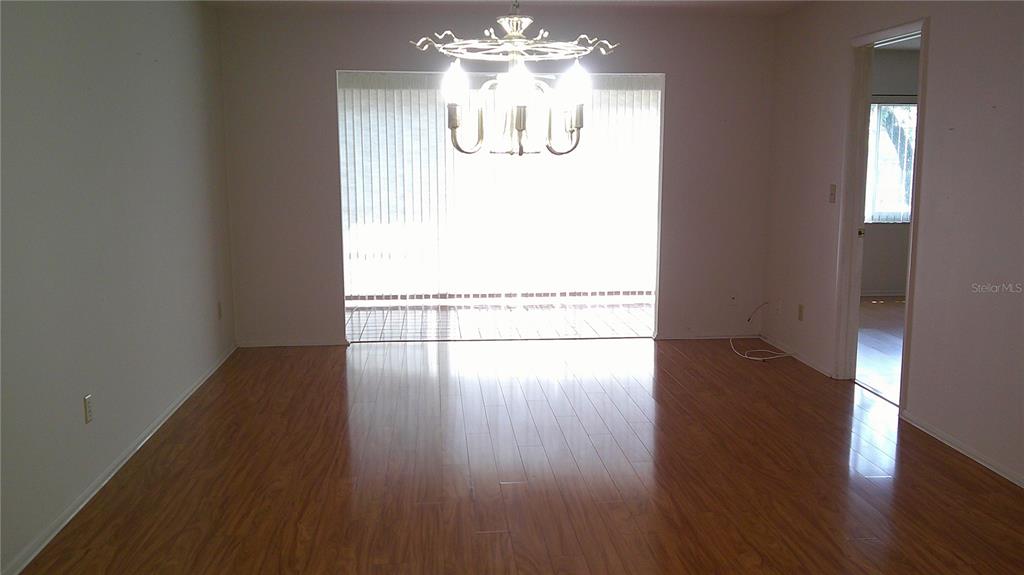 A dining room with wood-look flooring, a chandelier, and a sliding glass door to a patio — 3632 TEESIDE DRIVE, NEW PORT RICHEY, FL