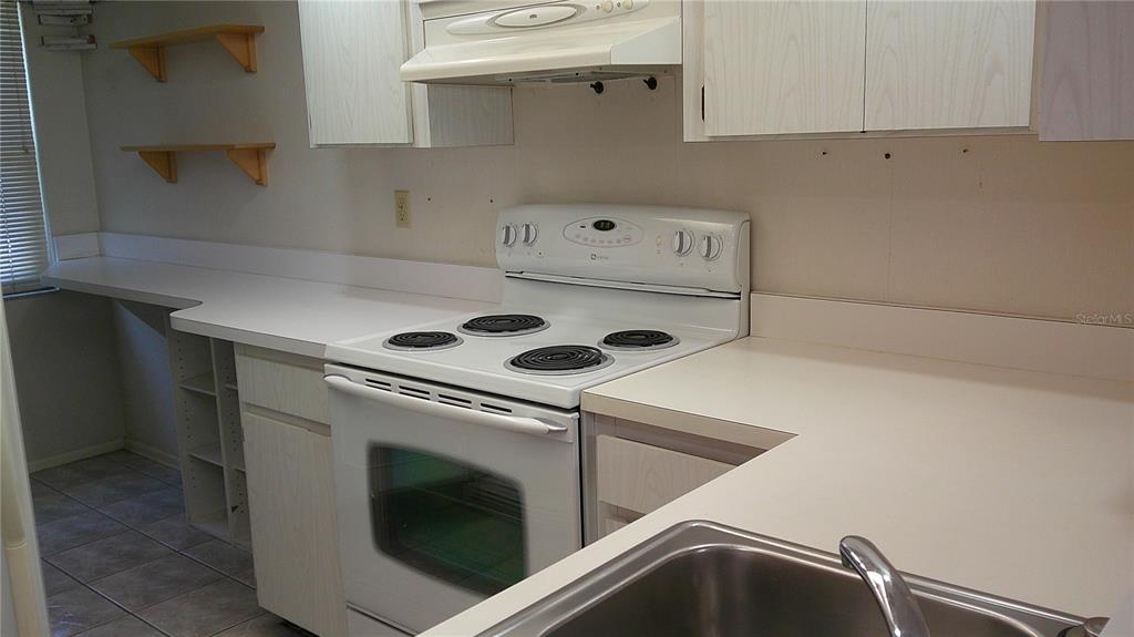 A kitchen features white cabinets, a white electric stove, and a stainless steel sink — 3632 TEESIDE DRIVE, NEW PORT RICHEY, FL