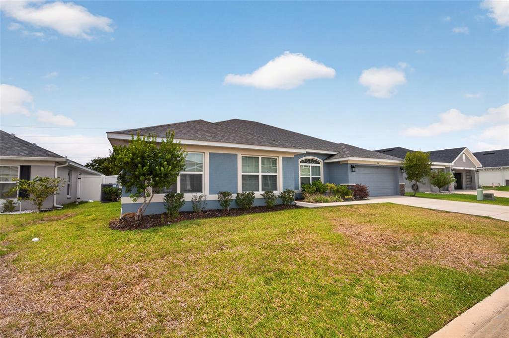 A blue single-story house with a two-car garage and a front lawn under a sky — 8356 SW 59TH TERRACE, OCALA, FL