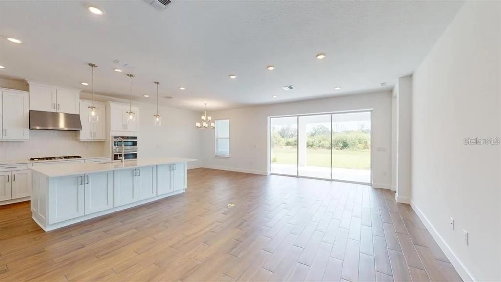 A modern kitchen with a large white island opens into a spacious, light-filled living area — 4911 CASERTA COURT, PALMETTO, FL