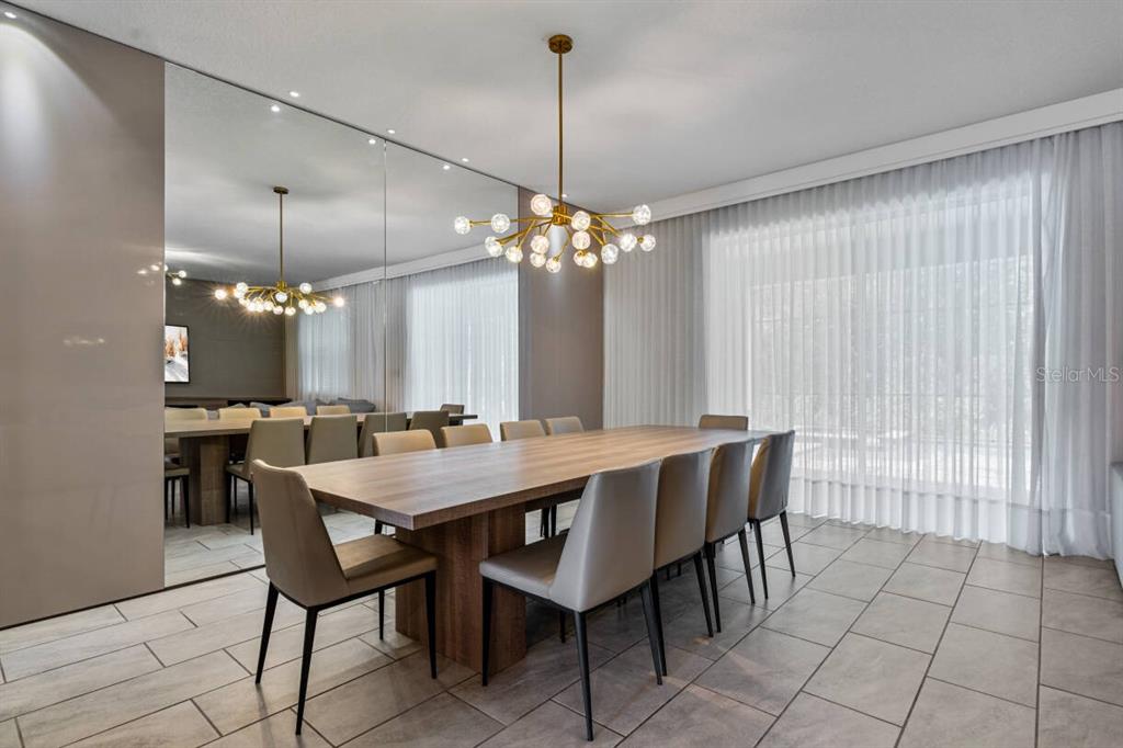 A dining room features a long wooden table, modern chairs, a chandelier, and mirrored walls — 2830 STOREY COVE AVENUE, KISSIMMEE, FL