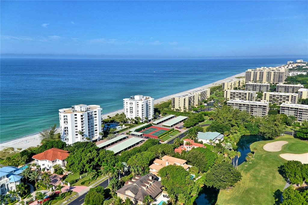 An aerial view shows beachfront condominiums, tennis courts, and a golf course near the ocean — 1000 LONGBOAT CLUB ROAD UNIT 304, LONGBOAT KEY, FL