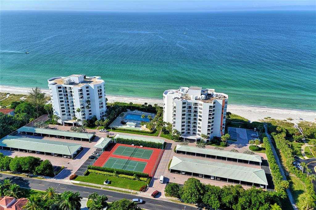 An aerial view shows two beachfront condominium towers with a swimming pool and tennis courts — 1000 LONGBOAT CLUB ROAD UNIT 304, LONGBOAT KEY, FL