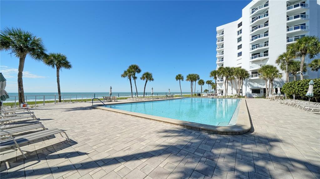 A swimming pool sits on a paved deck next to a white high-rise building — 1000 LONGBOAT CLUB ROAD UNIT 304, LONGBOAT KEY, FL