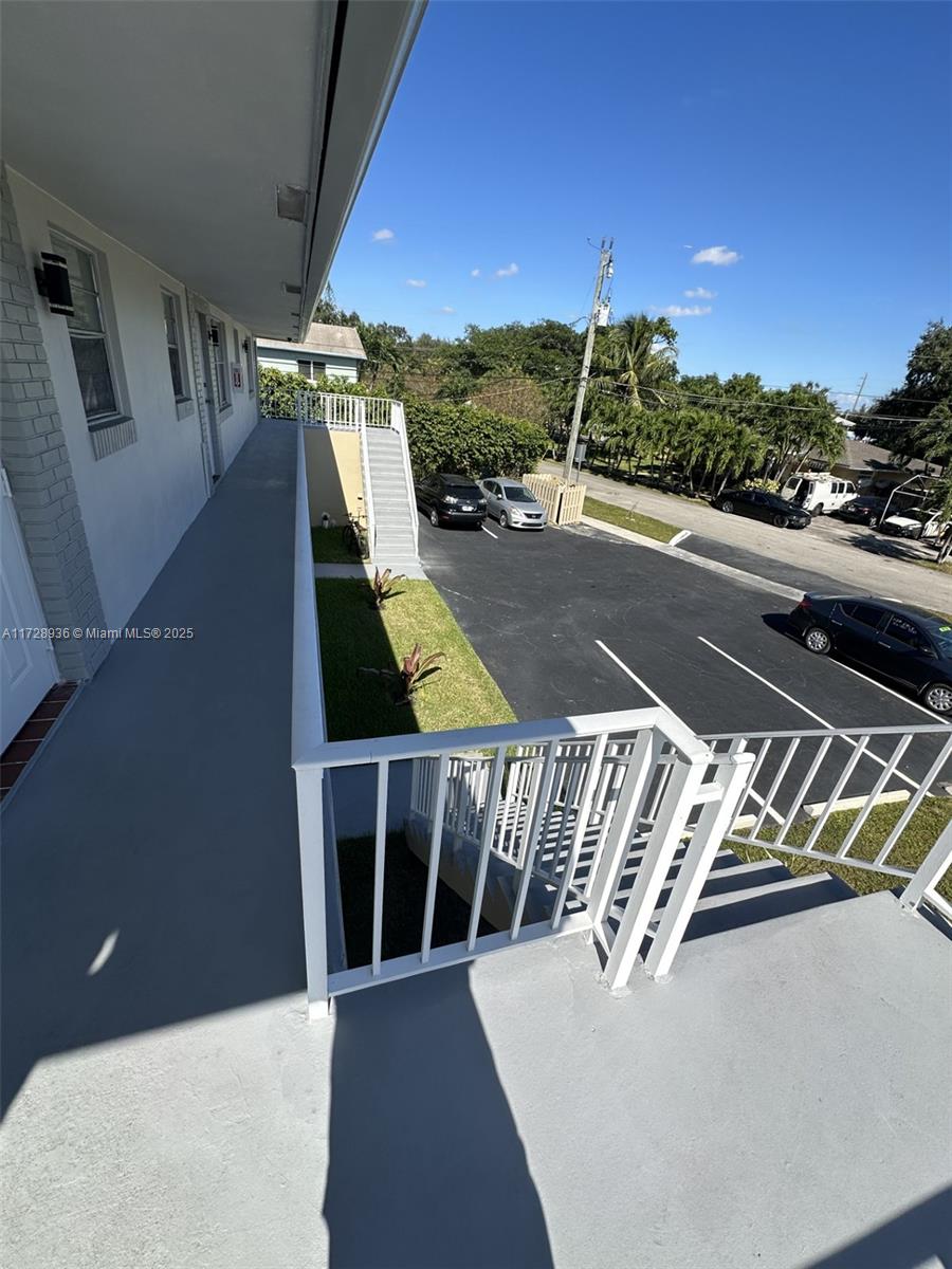 An elevated outdoor walkway overlooks a parking lot with several parked cars — 6101 Garfield St, Hollywood FL 33024, HOLLYWOOD, FL
