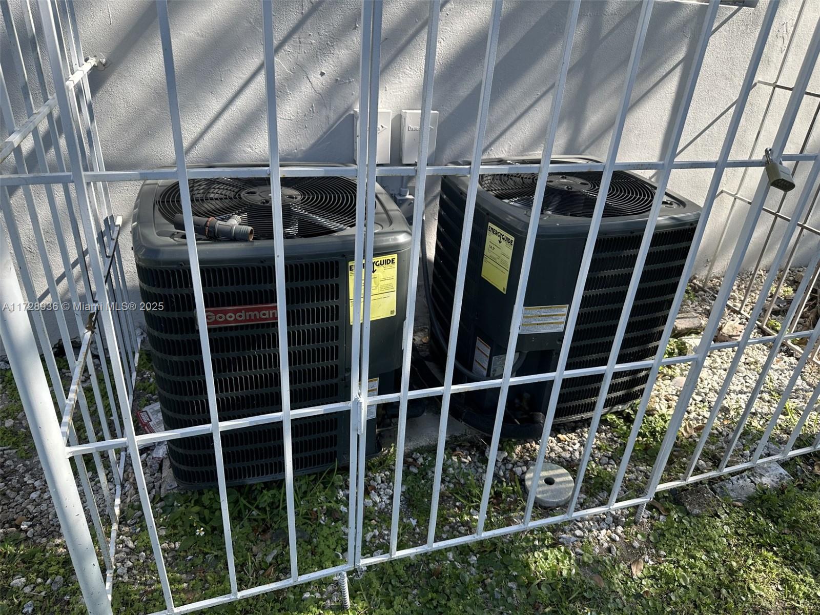 Two outdoor air conditioning units are enclosed within a white metal security cage — 6101 Garfield St, Hollywood FL 33024, HOLLYWOOD, FL