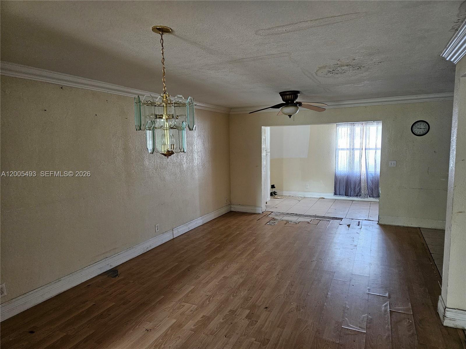 An empty room features wood-look flooring, a brass chandelier, and a ceiling fan — 1419 NW 80th Ave # F, Margate FL 33063, MARGATE, FL