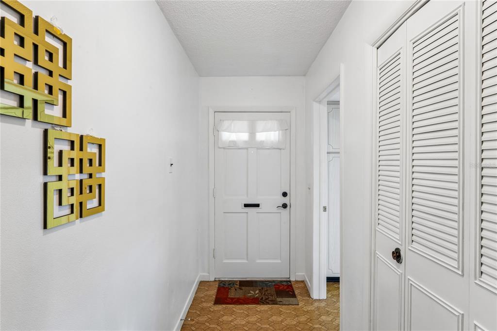 An entryway features white walls, a front door, a louvered closet door, and patterned flooring — 1611 S LAKE AVENUE UNIT 1, CLEARWATER, FL
