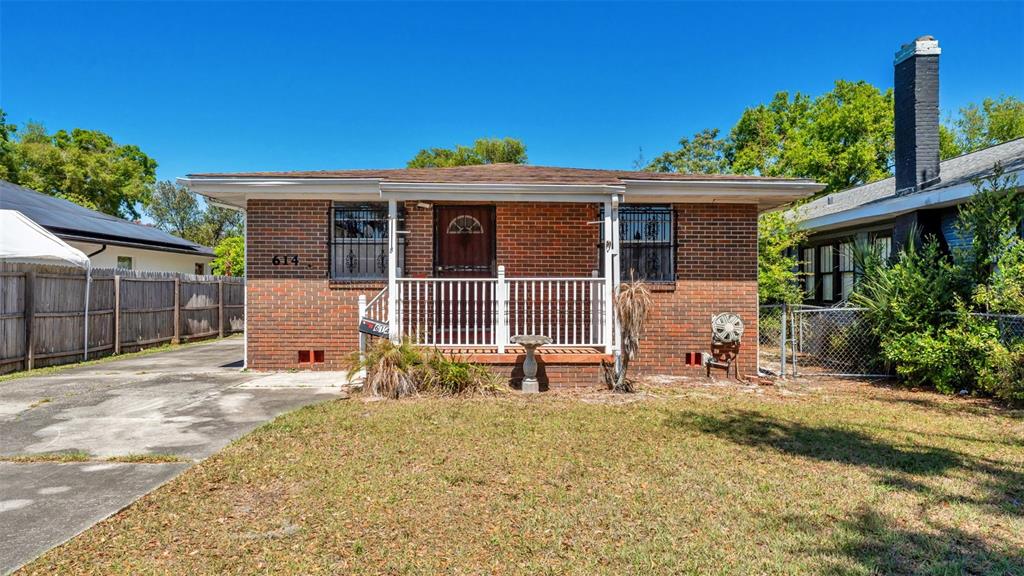 A single-story brick house features a front porch, a concrete driveway, and a fenced yard — 614 E CRAWFORD STREET, LAKELAND, FL