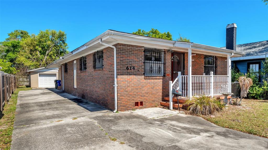 A single-story brick house features a front porch, a concrete driveway, and a detached garage — 614 E CRAWFORD STREET, LAKELAND, FL