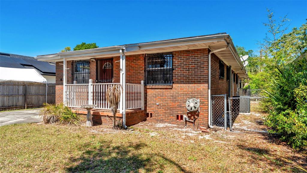 A single-story brick house features a front porch with white railings and a fenced yard — 614 E CRAWFORD STREET, LAKELAND, FL