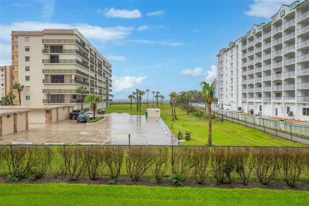 An exterior view shows two large apartment buildings separated by a parking lot and lawn — 1700 N ATLANTIC AVENUE UNIT 126, COCOA BEACH, FL
