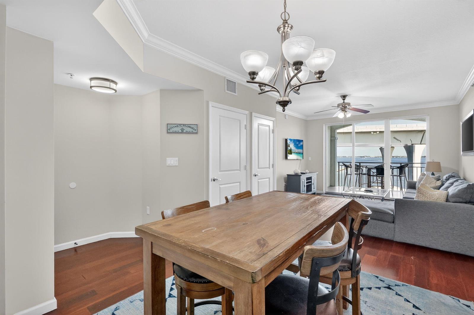 A dining area with a wooden table sits before a living room and balcony view — 415 NW Flagler Avenue # 403, Stuart FL 34994, STUART, FL