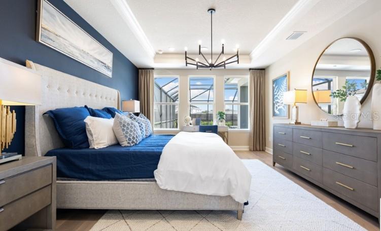 A bedroom features a blue accent wall, a tufted headboard, and a large round mirror — 11270 KINGLY LANE, ODESSA, FL